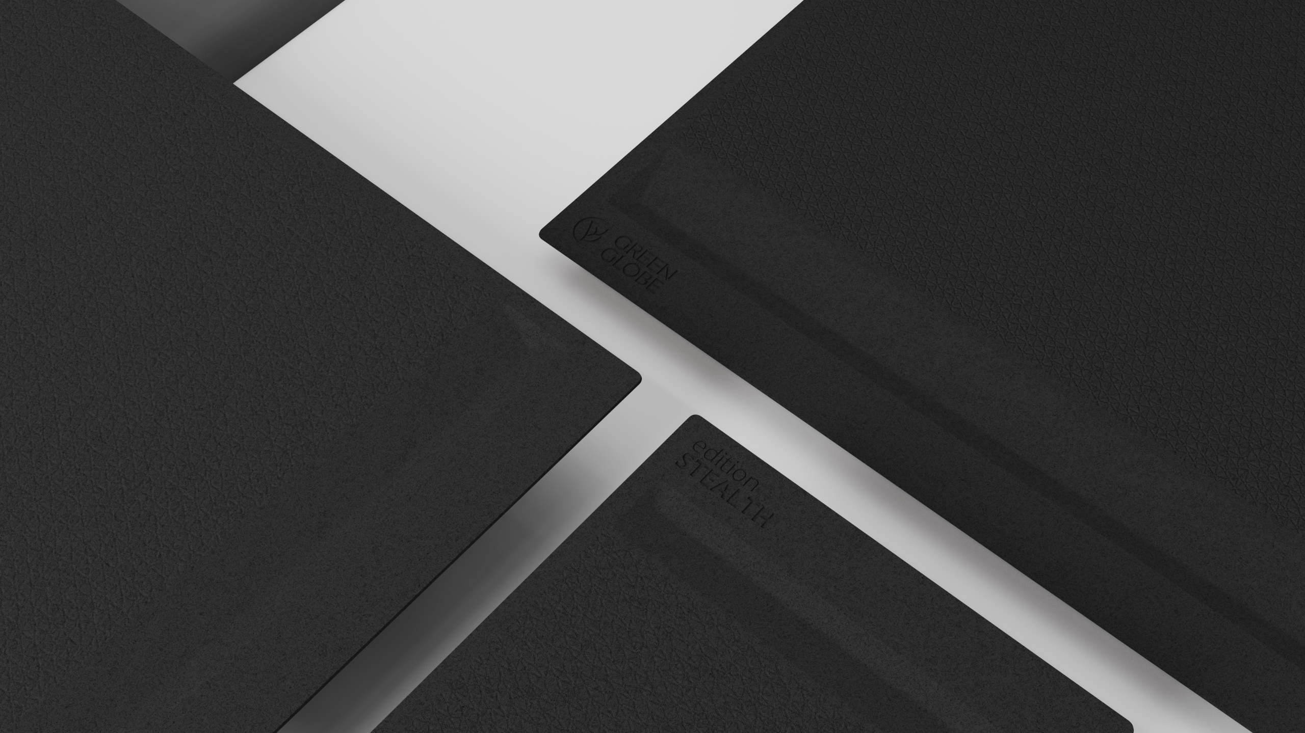 3 verschieden große schwarze GREEN GLOBE Cutting Boards der edition STEALTH liegen auf einem weißen Küchentisch.
